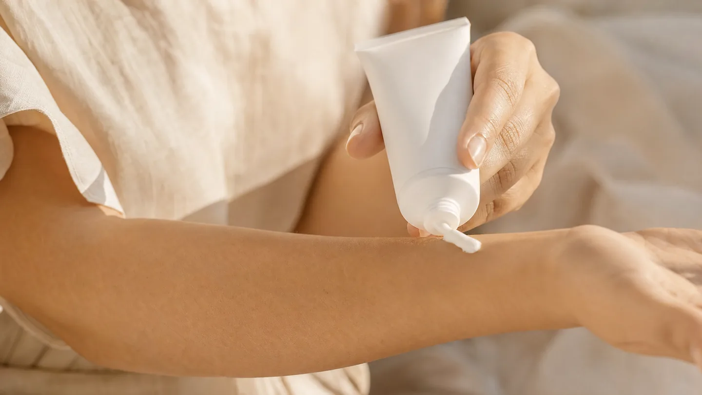 Auftragen einer Creme aus einer unbeschrifteten Tube auf einen Unterarm